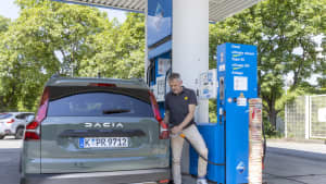 Ein Mann steht an einer Tankstelle neben dem LPG Dacia Jogger und betankt ihn mit LPGAutogas