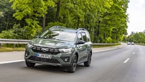 Grüner LPG Dacia Jogger fährt auf einer Straße neben einem Wald und wird mit LPG-Autogas betrieben