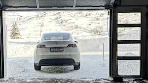 Tesla Model Y vor der am Tor der Hotelgarage in der Winterlandschaft von Obertauern  