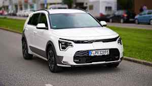 Ein weißer Kia fährt eine Straße entlang und testet die Reichweite des Elektroautos.