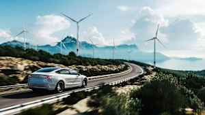 Ein weißes Auto fährt auf einer Straße die Küste entlang durch eine Landschaft aus Bergen und Windrädern, was die Vorteile ein Elektroauto oder Hybridauto zu leasen widerspiegelt.