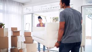 Pärchen trägt Sofa zum Umzugstransporter