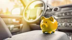 Ein gelbes Sparschwein steht auf der Mittelkonsole eines Autos, denn mit der richtigen kfz-versicherung kann man sparen
