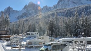 Ein Caravan Park ist voller Wohnmobile im Winter in einem Wald voller Schnee, denn mit dem Camping Ratgeber findet man leicht Campingplätze