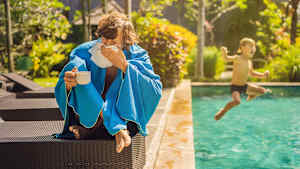 Krank am Pool im Urlaub. Das kann teuer werden. Dagegen hilft nur ein Auslandskrankenschutz.