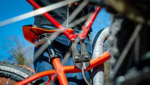 Eine Person schneidet mit einem Bolzenschneider ein Fahradschloss von einem orangem Fahrrad auf, ein weiterer Grund für eine Fahrradversicherung