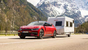 Elektroauto fährt mit einem Wohnwagen auf einer Straße