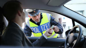 Polizist kontrolliert Fahrzeugschein eines Autofahrers