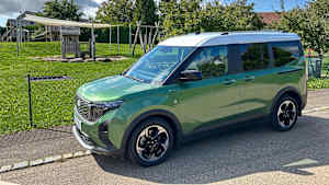 Ford Tourneo E-Courier stehend neben einer Wiese, Seitenansicht.