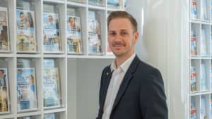 Markus Elter, Geschäftsstellenleiter ADAC Südbayern, vor einem Flyer und Zeitschriften-Display