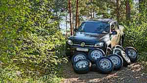 ADAC Ingenieur Christoph Pauly sitzt in einem Auto, vor dem Auto sind verschiedene All Terrain Reifen abgelegt
