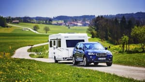 BMW mit Wohnanhänger fährt auf Landstraße