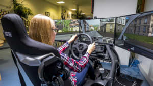 Eine junge Frau sitzt in einem Fahrsimulator