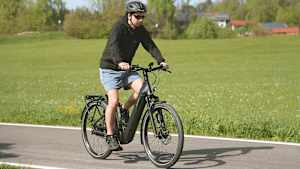 EIn Mann fährt in frühlingshafter Landschaft ein E-Bike von Kalkhoff