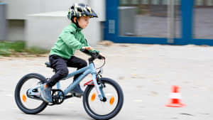 Ein Junge fährt auf einem 16 Zoll Fahrrad auf eine Pylone zu