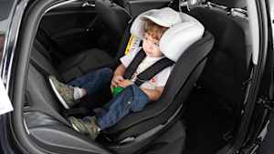 Ein Kind sitzt in einem Kindersitzt auf der Rückbank eines Autos
