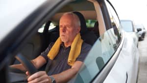 Ein Mann sitzt bei Hitze im Auto
