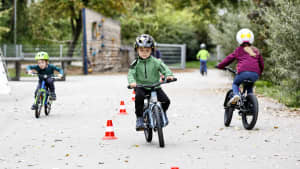 Kinder fahren mit einem 16 Zoll Fahrrad auf dem Schulhof