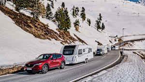 Autos mit Wohnwagen fahren durch eine Winterlandschaft