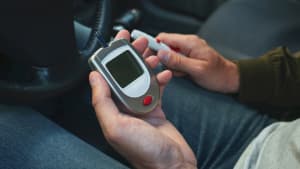 Glucometer und Lanzenstift in den Händen eines Mannes