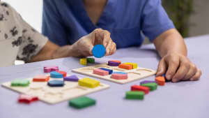 Eine Pflegekraft spielt mit einer alten Person ein Spiel zur Demenzvorbeugung