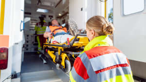 Eine Rettungssanitäterin schiebt einen Mann auf einer Trage in den Krankenwagen