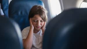 Mädchen hält sich im Flugzeug die Ohren zu