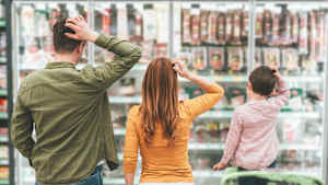 Eine Familie steht vor einem Supermarktregal und kratzt sich am Kopf.