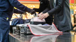 Ein Sicherheitsbeamter am Flughafen überprüft das Handgepäck
