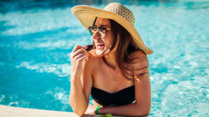 Eine Frau isst am Pool frisches Obst