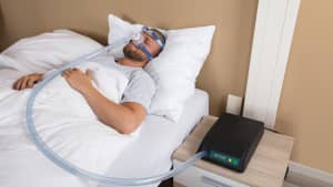 Mann schläft mit CPAP Maske