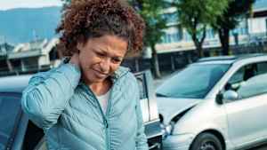 Eine Frau hält sich ihr Genick nach einem Auffahrunfall mit einem zweiten Fahrzeug