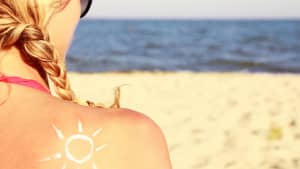 Eine Sonnencreme auf dem weiblichen Rücken am Strand