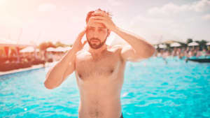 Ein Mann vor einem Pool fühlt sich schlecht