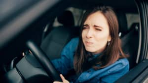 Eine junge Frau verzieht das Gesicht im Auto