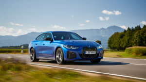 Der neue blaue BMW i40 M50 fahrend von der Seite auf einer Landstrasse in den Bergen