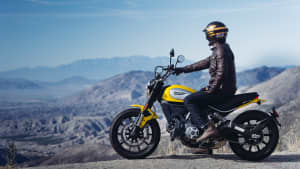 Ein Mann sitzt auf einer Ducati Scrambler Icon, die man von der Seite sieht