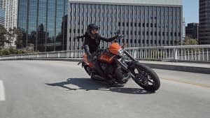 Eine Harley Davidson fährt auf einer Strasse, im Hintergrund stehen moderne Häuser