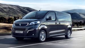Front und Seitenansicht eines fahrenden Peugeot e-Traveller