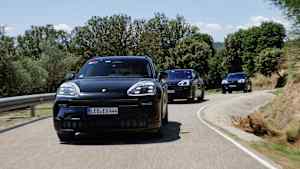 Frontansicht drei fahrender Porsche Cayenne E auf einer Landstraße bei sonnigem Wetter