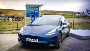 Ein Tesla steht vor einer Elektrotankstelle