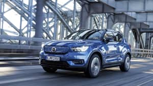 Neuer blauer Volvo XC40 Recharge während der Fahrt über eine Stahträgerbrücke