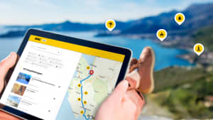 Ein Mann sitzt mit seinem tablet im Urlaub auf einem Berg