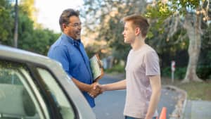 Fahrlehrer gratuliert Schüler zur bestandenen Führerscheinprüfung
