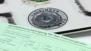entwertetes Autokennzeichen und Anmeldebescheinigung für den Fahrzeughalter