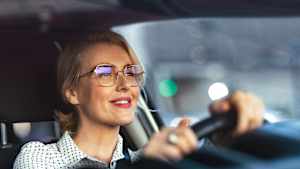 Lächelnde Business Frau fährt mit ihrem Auto durch die Stadt