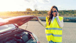 Eine Frau mit Warnweste hat eine Autopanne