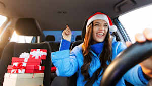 Eine Frau mit Weihnachtsmannmütze singt beim Autofahren