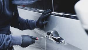 Nahaufnahme Autodieb Hand halten Schraubendreher Sabotage Ruck und Handschuh schwarz stehlen Auto versucht Türgriff zu sehen, ob Fahrzeug entriegelt ist und versucht, ins Innere einzudringen