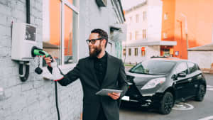 Mann im Anzug betankt Elektroauto